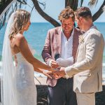 Close-up of Zoe and Deon during their Oceanic Dream package wedding ceremony on the lush green lawn by the ocean exchanging vows.