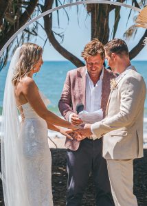 Close-up of Zoe and Deon during their Oceanic Dream package wedding ceremony on the lush green lawn by the ocean exchanging vows.