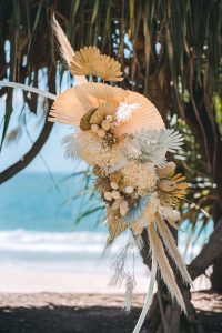 Luxe white circle arbour with neutral-colored dried florals against the ocean backdrop at Zoe and Deon’s Noosa wedding.